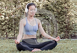 Asian woman doing meditation and listening to music in garden