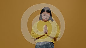 Asian woman doing praying gesture with hands and begging