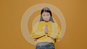 Asian woman doing praying gesture with hands and begging