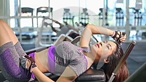 Asian woman doing sit ups fitness exercise at gym