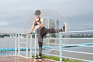 asian woman doing stretching exercises outdoors along city sidewalk