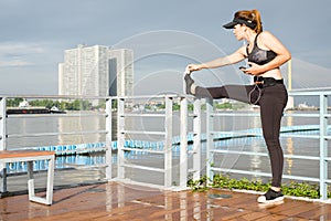 asian woman doing stretching exercises outdoors along city sidewalk