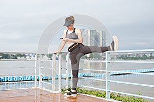 asian woman doing stretching exercises outdoors along city sidewalk