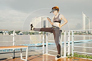 asian woman doing stretching exercises outdoors along city sidewalk in summer warm light