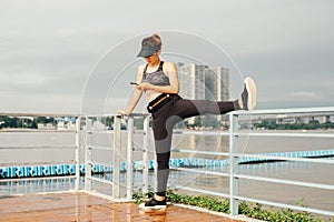 asian woman doing stretching exercises outdoors along city sidewalk in summer warm light