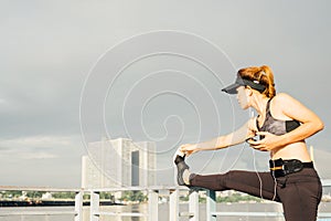 asian woman doing stretching exercises outdoors along city sidewalk in summer warm light