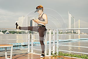 asian woman doing stretching exercises outdoors along city sidewalk in summer warm light