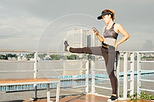 asian woman doing stretching exercises outdoors along city sidewalk in summer warm light