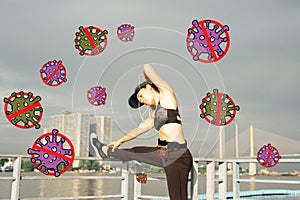 Asian woman doing stretching exercises outdoors along city sidewalk in summer warm light