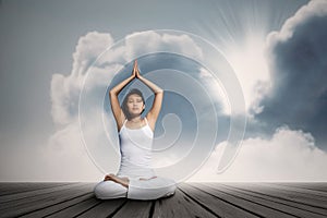 Asian woman doing yoga exercise under blue sky