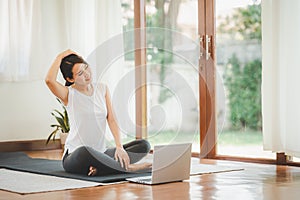 Asian woman doing yoga neck stretching online class at home