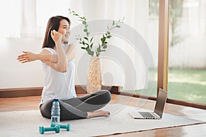 Asian woman doing yoga shoulder stretching online class at home