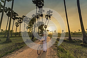 Asian woman dressed in traditional Vietnamese bicycle walk on sunset background