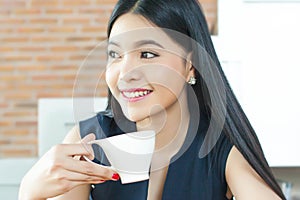 Asian Woman drinking coffee with smile on her face