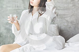 Asian woman drinking fresh water in bed after wake up in the morning
