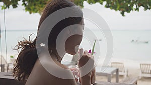 Asian woman drinking juice at beach bar. female feeling happy after having refreshment drink.