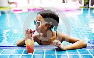 Asian woman drinking juice by the poolside