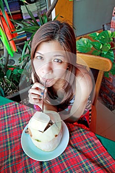 Asian woman drinking refreshment of young coconut