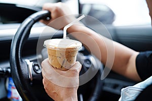 Asian woman driver hold ice coffee cup for drink in car, dangerous and risk an accident