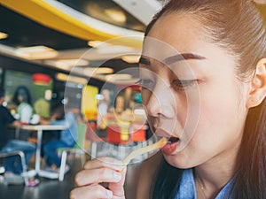 Asian woman is eating french fries.