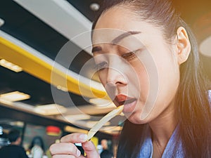 Asian woman is eating french fries.