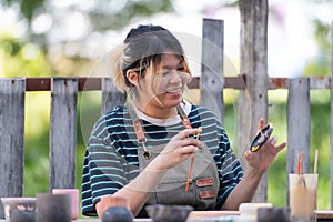 Asian woman is engaged in pottery making and clay painting activities