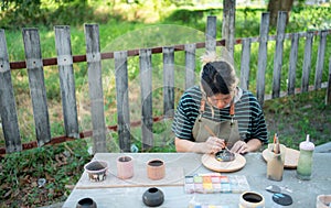 Asian woman is engaged in pottery making and clay painting activities