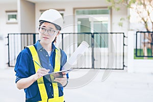 Asian woman engineer or architecture hold clipboard and looking at construction site or work place and checking audit checklist.