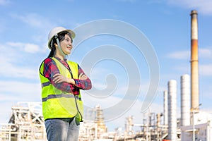 Asian woman engineer arm crossed and smile with confident looking forward to future with oil refinery plant factory in background