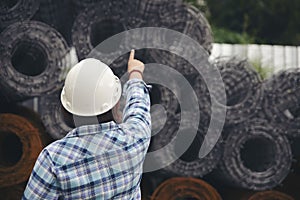 Asian woman engineer inspect in front of construction site. Civil Engineer wear safety hard hat pointing and checklist at building