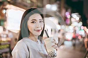 Asian woman enjoy bubble milk tea with street food in  Night Market