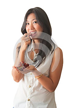 An Asian woman enjoy eating red grape