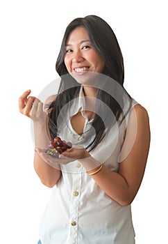 An Asian woman enjoy eating red grape