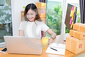 Asian woman enjoy herself while using  internet on laptop and phone in office. Business and marketing and part time concept.