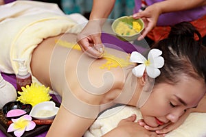 Asian woman enjoying a salt scrub massage at spa