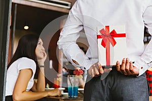 Asian woman expected to receive a surprise present gift box from man as a romantic couple for occasional anniversary celebration.