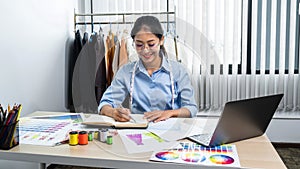 Asian woman fashion designer wearing glasses to drawing clothes sketch and working with fabric