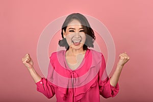 Asian woman feeling happy and excited on accomplish success on pink background.