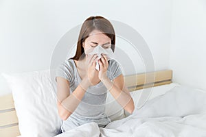 Asian woman feeling unwell and sneeze on bed