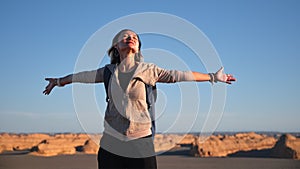 Asian woman female tourist backpacker enjoying yardang landforms landscape with open arms