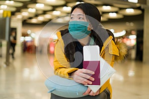 Asian woman flying in covid19 times - lifestyle portrait of young beautiful and tired Chinese girl in face mask waiting on airport