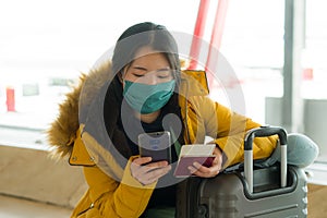 Asian woman flying in covid19 times - lifestyle portrait of young beautiful and tired Chinese girl in face mask waiting on airport