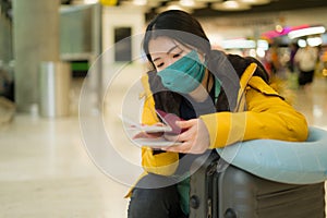 Asian woman flying in covid19 times - lifestyle portrait of young beautiful and tired Korean girl in face mask waiting on airport