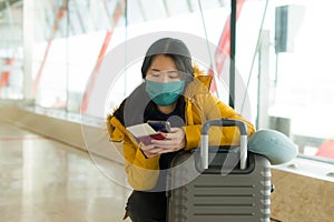 Asian woman flying in covid19 times - lifestyle portrait of young beautiful and tired Korean girl in face mask waiting on airport