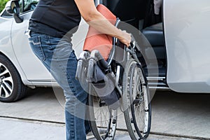 Asian woman folding and lift up wheelchair into her car. Accessibility concept