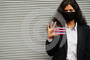 Asian woman at formal wear and black protect face mask hold Hawaii flag at hand against gray background. Coronavirus at country