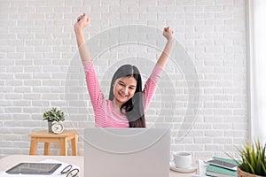 Asian woman freelancer raise arm up stretching in front of laptop on desk from work in home office,work at home.
