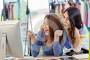 Asian woman with friend exciting hand pointing at computer screen for happy young SME business owner concept