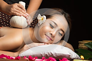 Asian woman getting thai herbal compress massage