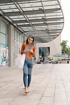 Asian woman go shopping and using mobile phone outdoor shopping mall